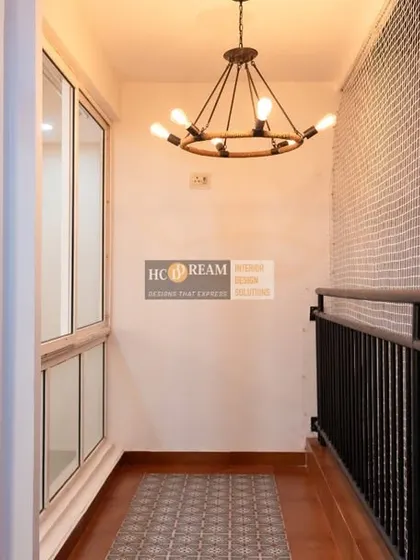 The balcony area in Deepak and Anju's home, featuring an industrial-style chandelier and a tiled accent wall, turning it into a stylish outdoor retreat.