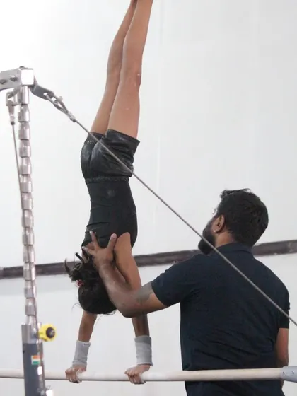 Hands-on coaching makes all the difference. Here, one of our expert coaches provides support during a challenging handstand on the uneven bars, ensuring safety and perfect form.