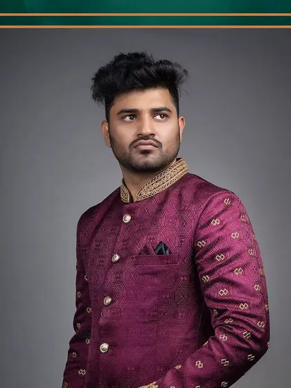 The groom's outfit: a rich maroon Jodhpuri suit that complements the bride's red attire.