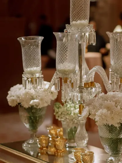 A beautiful glass candelabra centerpiece, surrounded by arrangements of white flowers. This classic decor element adds a touch of timeless elegance to any setting.