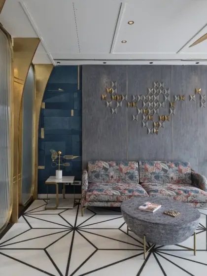 The lounge in the Screen House overlooks the living room, featuring a striking floral-print sofa and bespoke heart-shaped artwork on the wall. A brass and glass partition adds a touch of refined elegance.