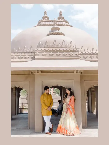 A classic pre-wedding portrait set against the majestic architecture of Jaipur. The complementary colors of their outfits pop against the neutral stone.