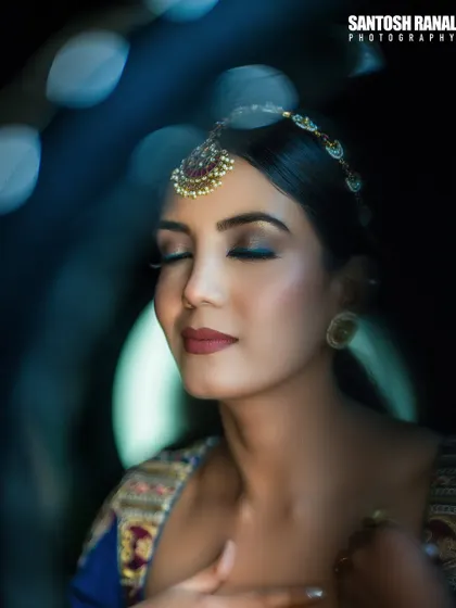 An artistic and serene portrait of a bride with her eyes closed, captured with creative blue lighting and bokeh effects.