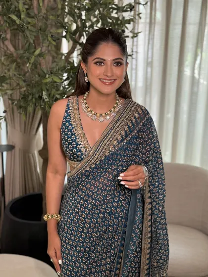 A smiling portrait of the guest, showcasing her classic makeup look with a simple bindi and soft lip color.