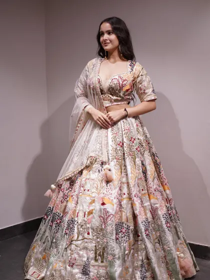 A full view of the artistic cream lehenga, showing how the colorful embroidery creates a beautiful story across the fabric.