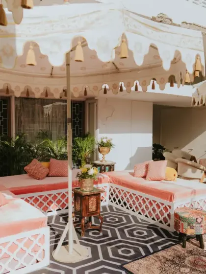 A chic outdoor lounge setup for the at-home Haldi, with custom-made daybeds, patterned rugs, and elegant fringed umbrellas.