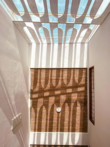 Light is one of our most important materials. Here, a custom-designed geometric skylight casts dramatic patterns across an exposed brick wall, transforming the space and creating a living artwork that changes with the sun.