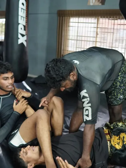 A coach demonstrating a guard pass on a student. We believe in a hands-on approach to teaching, ensuring every student understands the technique.