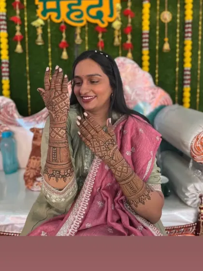 A smiling client showing her full bridal mehndi during her home ceremony.
