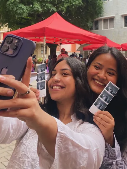 A selfie of two friends with their freshly printed photo strip. It's all about sharing the fun.