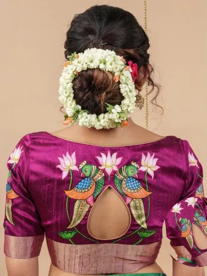 The back of this magenta blouse is a showstopper, featuring a keyhole cutout adorned with hand-painted peacock and lotus motifs.