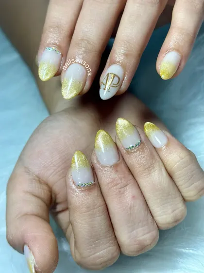 Making engagement nails extra special with personalized initials. For this bride-to-be, we did a beautiful golden ombre with delicate rhinestones and her partner's initials in a stylish monogram.