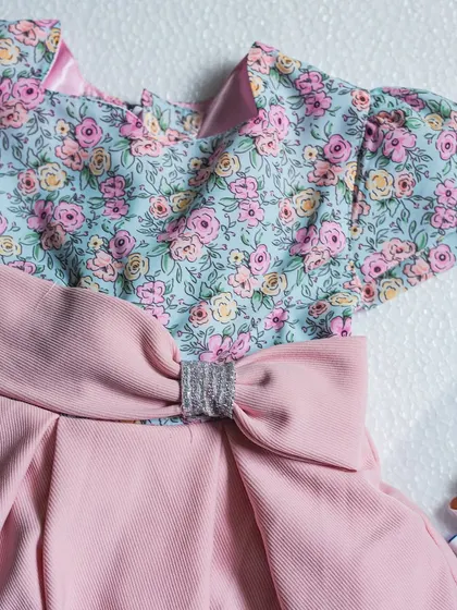 A beautiful combination of a soft floral print bodice and a dusty pink skirt. The look is tied together with a matching pink bow featuring a sparkly silver center.