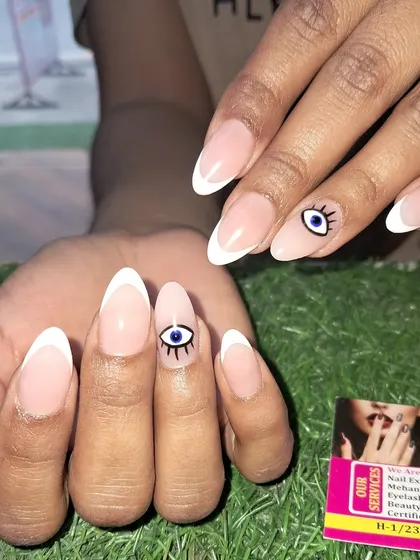 A clean and simple evil eye design paired with a classic white French tip on almond nails.