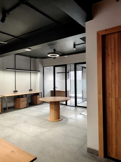 This open-plan office highlights our industrial-chic aesthetic, featuring an exposed ceiling, polished concrete floors, and sleek linear lighting. The layout is intentionally designed to foster collaboration while maintaining a clean, modern, and spacious feel.