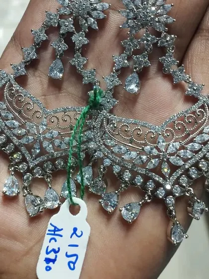 A pair of grand, silver-plated American Diamond chandbali earrings. The intricate design and sparkling stones make them a perfect choice for a reception or cocktail party.