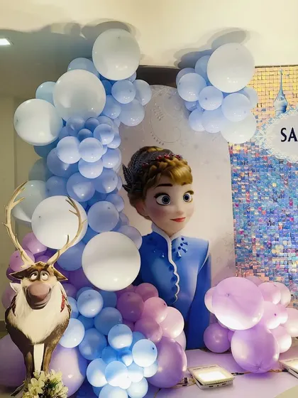 A close-up of the blue balloon garland and character cutouts from the Frozen theme.