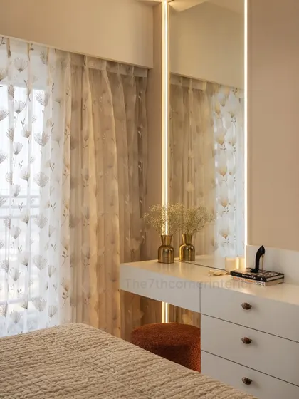 A cozy and elegant vanity corner in a bedroom, featuring a sleek white dressing table with golden knobs and a large mirror with soft, integrated LED backlighting for perfect illumination.