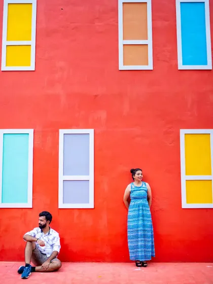 A fun and creative pre-wedding shot using a brightly colored wall with multi-colored windows as a playful backdrop.