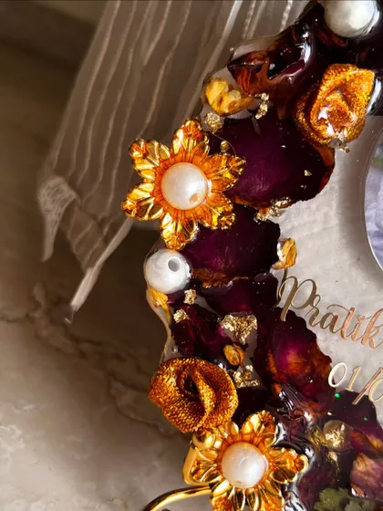 A close-up of a cute, budget-friendly photo frame made from an engagement garland. The golden flowers and pearls add a touch of elegance.