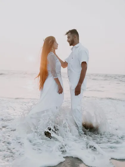 An intimate shot of a couple standing in the waves during their beach pre-wedding session. The soft light and water movement add a dreamy quality to the portrait.