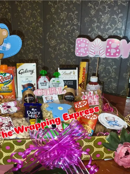 A celebration hamper packed with snacks like Real juice, Galaxy chocolate, Pringles, and various dry fruits.
