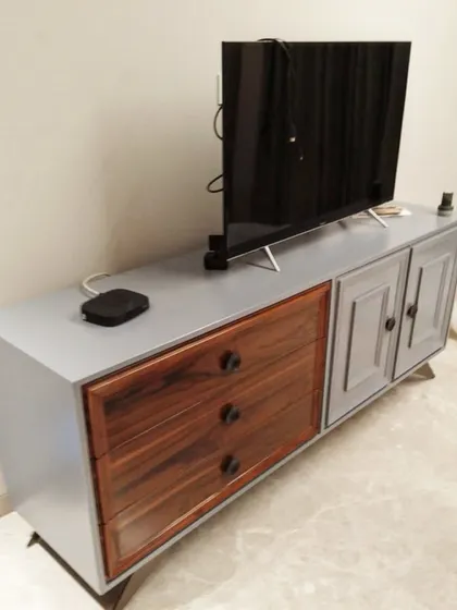 A TV unit we delivered to a client in Greater Kailash, Delhi. This piece features a two-tone design with a grey-painted body and natural wood veneer drawers, creating a modern yet warm look.