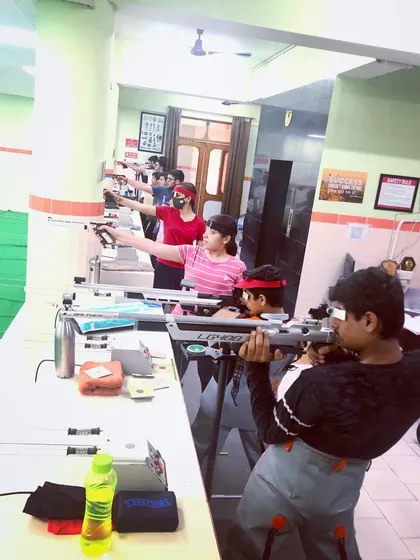 A mixed group of young shooters practicing with both pistol and rifle, showing the diversity of talent at the academy.
