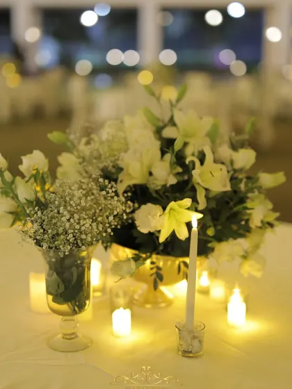 Another beautiful centerpiece, with white lilies and baby's breath illuminated by the warm light of candles, creating a dreamy tablescape.