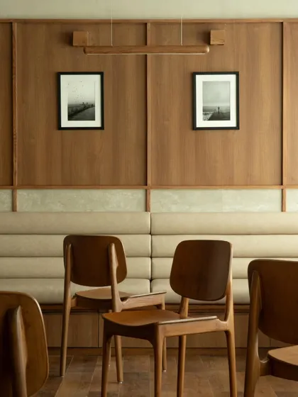 The linear seating arrangement at QBF Coffee, with continuous upholstered benches against wood-paneled walls. This efficient and elegant solution maximizes space while maintaining a clean, uncluttered aesthetic.