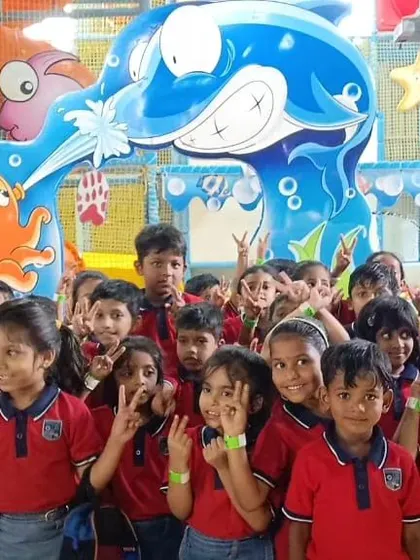 A large group of students posing for a photo during their field trip. The underwater-themed entrance arch at our Bannerghatta center makes for a great photo opportunity.