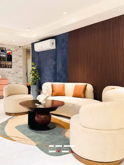 This cozy seating area uses a mix of textures and colors, including a deep blue accent wall and warm wood paneling, to create a distinct and inviting corner within a larger living space.