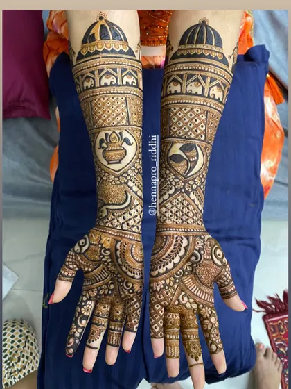A simple yet elegant bridal design. This piece uses negative space effectively, with heart-shaped frames for the kalash and conch shell motifs, surrounded by delicate patterns.