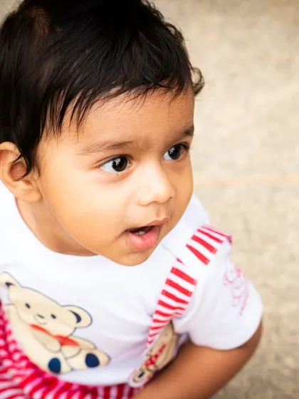A close-up portrait of a baby outdoors, capturing their innocent and curious gaze.