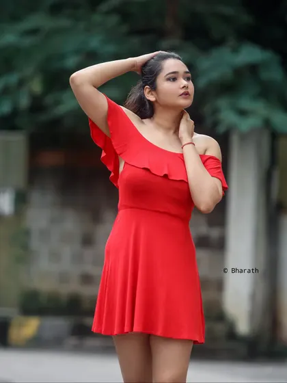 A confident outdoor portrait with a simple, blurred background. The focus is entirely on the subject's expression and pose.