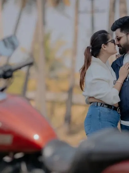 A cool and edgy pre-wedding shot in Goa. The couple shares an intimate moment, with a red motorcycle blurred in the foreground, adding a pop of color and attitude.