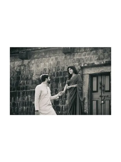 A classic romantic gesture captured in timeless black and white, as the groom-to-be takes his partner's hand.
