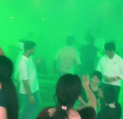 A corporate party filled with green light and smoke, creating a surreal, high-energy atmosphere.