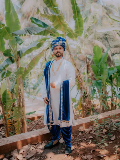 A full-length portrait of the groom, showcasing his complete traditional wedding outfit.
