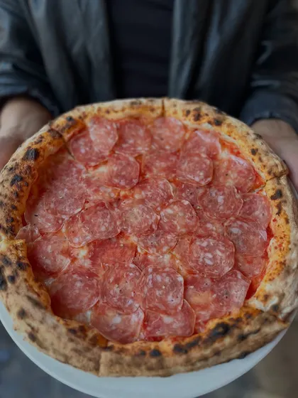 Holding up our Truffle Salami pizza. It's a handful of gourmet goodness.