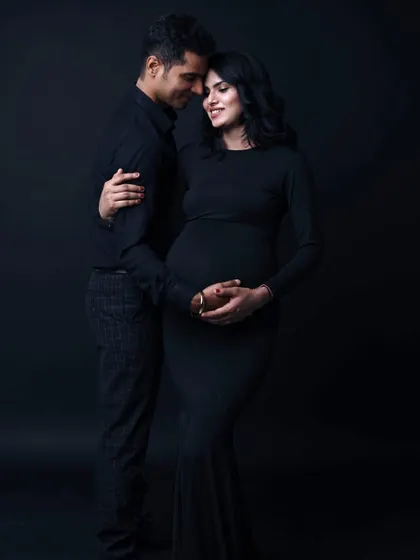 Timeless, classic, and elegant. A simple black dress against a dark backdrop puts all the focus on the couple's connection and the beautiful silhouette of the baby bump.