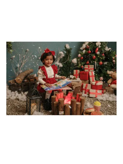 A portrait of the little girl reading her book by the Christmas tree and presents.