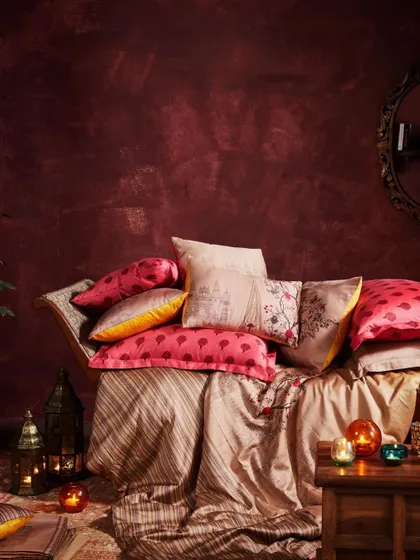A styled shot of cushions and throws from the wedding collection. The warm lighting from lanterns and the plush textures create a festive and inviting atmosphere.