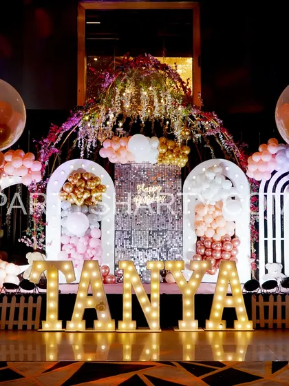 A beautiful stage setup for a teddy bear theme, with a sparkling sequin backdrop, floral arch, and large marquee letters.
