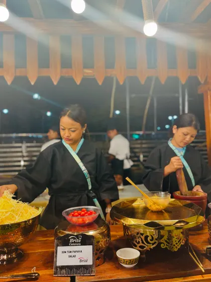 A closer look at the chefs preparing Som Tom salad, highlighting the fresh ingredients like cherry tomatoes and shredded papaya.