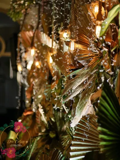 A detail shot of the hanging decor, featuring Edison bulbs and crystals intertwined with gold-painted dried leaves for a warm, sparkling effect.