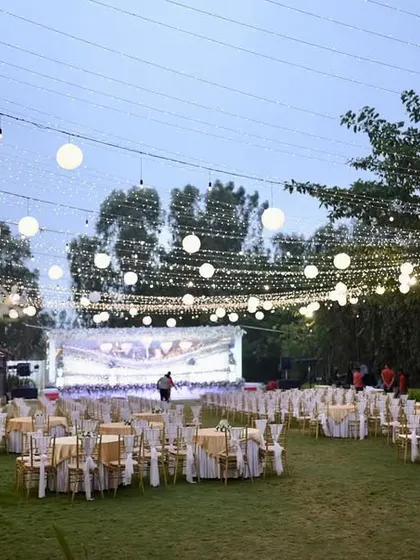 An outdoor reception setup with a canopy of string lights and paper lanterns, creating a warm and inviting atmosphere.