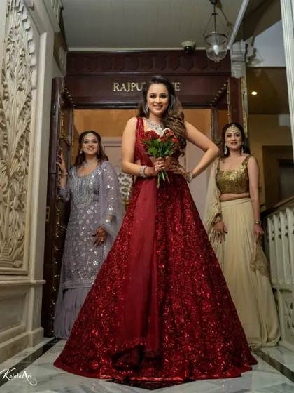 A confident bride in a stunning red gown, ready for her reception. Her pose and expression exude style.