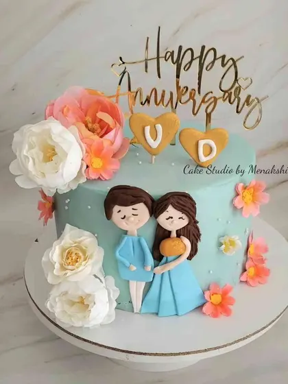 Celebrating an anniversary with a personal touch. This cute cake features hand-drawn style figures of the couple, surrounded by fresh flowers and topped with a custom 'Happy Anniversary' sign.