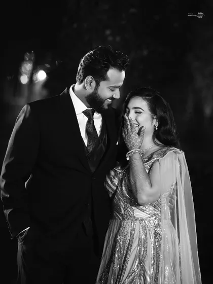A candid black and white shot capturing a moment of pure laughter and joy. This image proves that even the most glamorous shoots have space for authentic, unposed emotion.